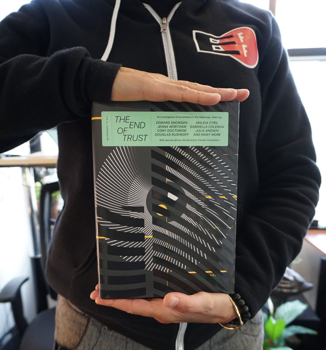 A photo wearing of a person wearing an EFF hoodie and holding the hardcover copy of The End of Trust