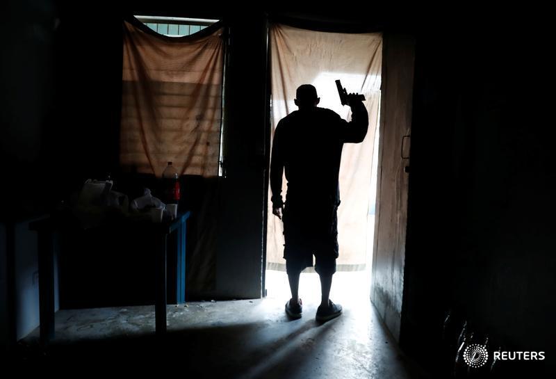reuterspictures's tweet photo. (Warning: graphic content) A member of the MS-13 gang looks out from a house as police patrol outside in San Pedro Sula, Honduras. Read more about the terror of gang violence that drives migrant caravans northward: https://t.co/A31g2efF5P 📷 Goran Tomasevic https://t.co/eJc96uu36P