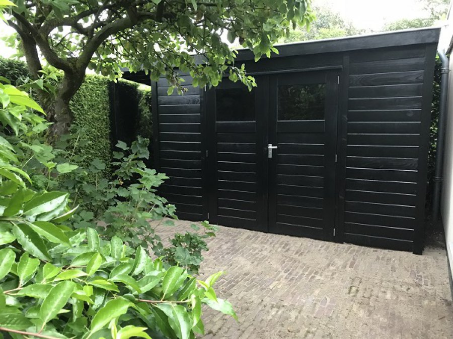 Prachtig mooi zwart geverfd tuinhuis met een kleine overkapping.