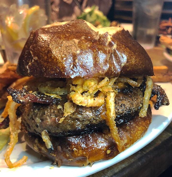 Our burger of the month is the Bergen Pepper Burger. Coffee spice-rubbed burger patty, as always our signature half pound ground chuck and short rib blend patty, topped with Dr Pepper BBQ sauce, onion straws and bacon. Placed atop a bed of arugula and tomato on a pretzel bun.