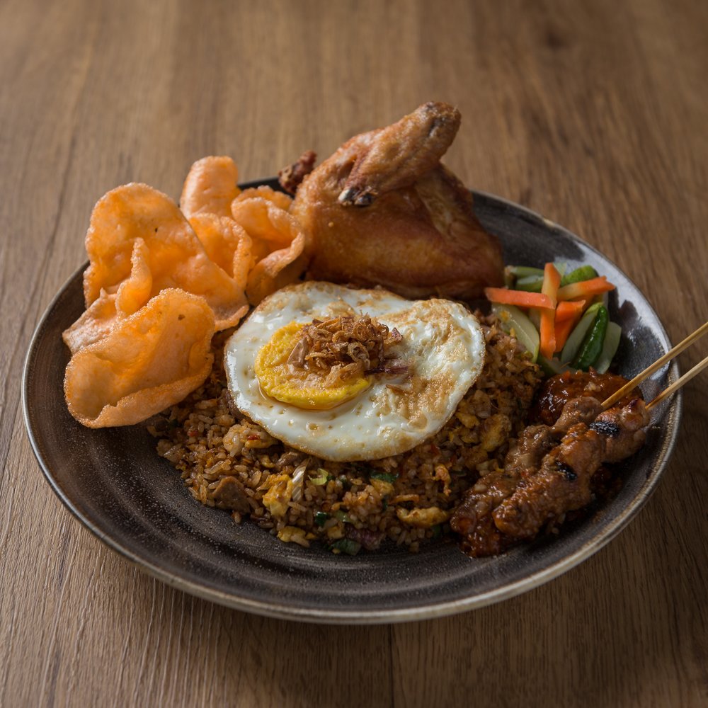 A special take on a common Indonesian dish that fits perfectly to be enjoyed at any given moment. Nasi Goreng Istimewa combines stir fried rice with egg and spices topped with fried, soy-marinated chicken, chicken satay, sunny side up and crispy krupuk.