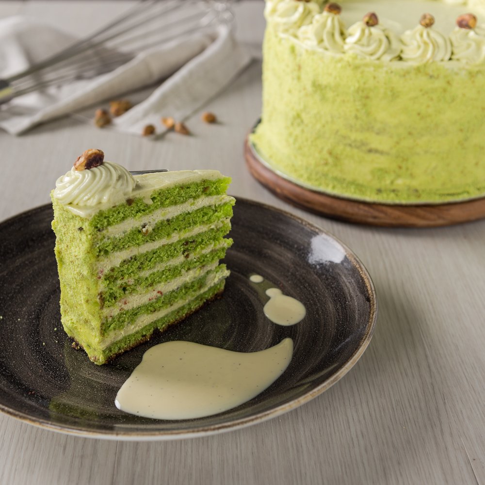 The Pistachio Cake is a sweet treat loved through generations. Layers of pistachio sponge cake and pistachio buttercream are stacked tall and sprinkled with pistachio crumbs.