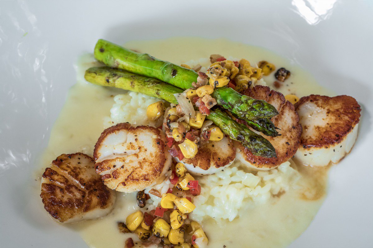Nom Nom Nom.. Pan Seared Scallops, served over Parmesan Risotto and paired with our Roast Corn Salsa and Balsamic Grilled Asparagus. Finished with a creamy garlic beurre blanc.
