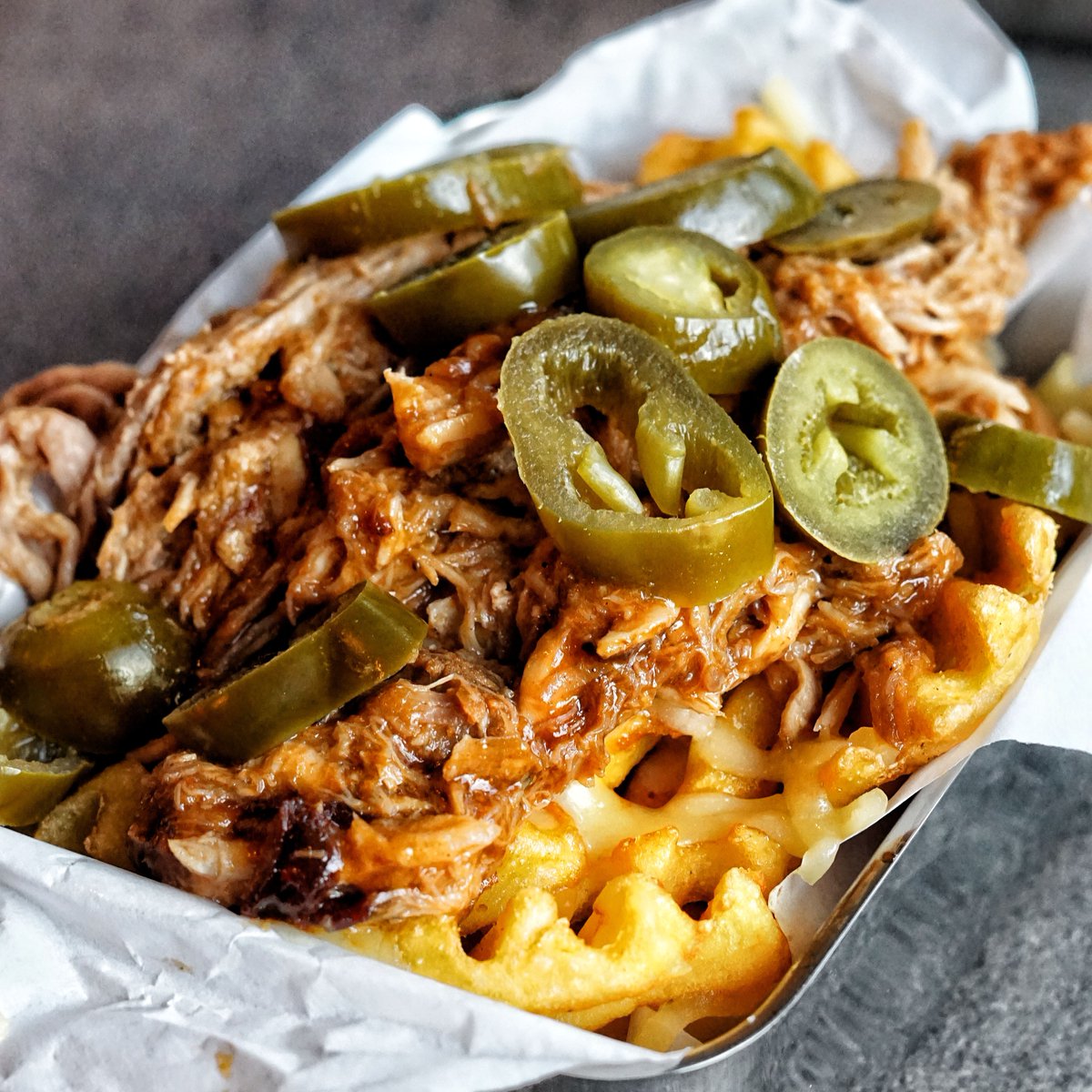 Waffle fries topped with melted cheese, sweet pulled pork and spicy jalapeños 🤤🔥

📸: @Jakesfoodbible
