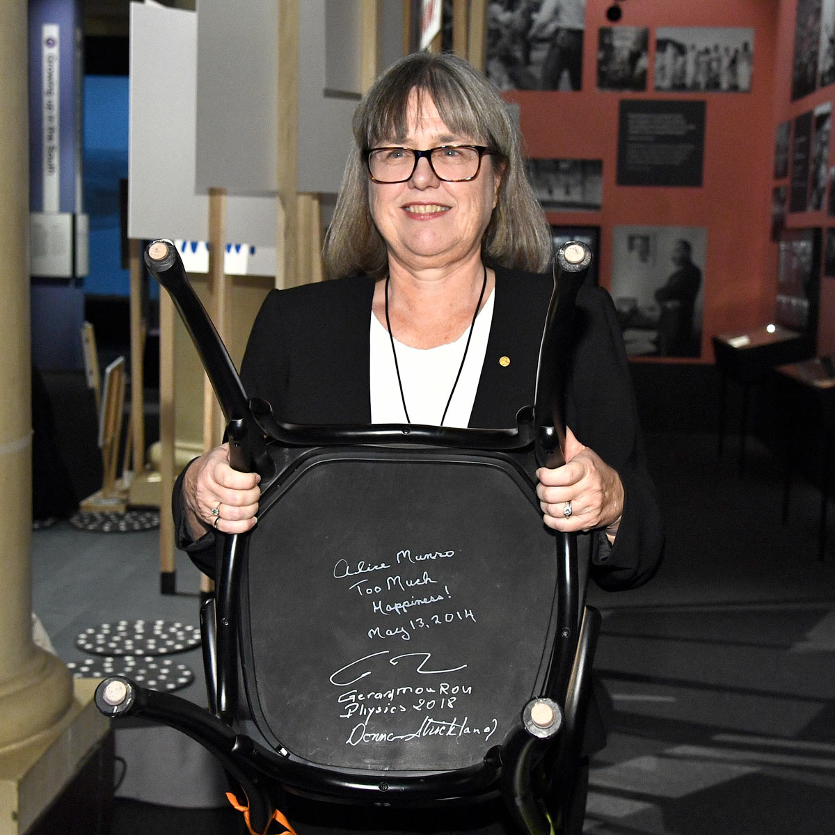 Donna Strickland holds up a chair to show the signatures underneat