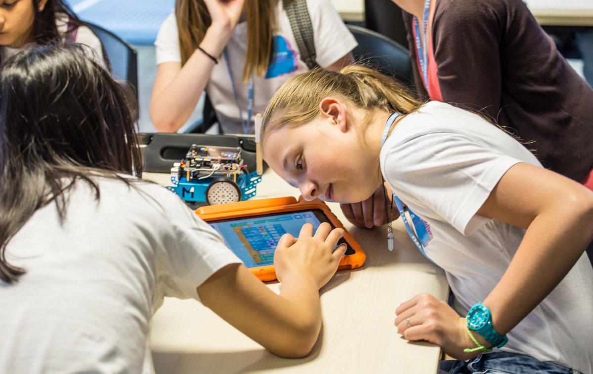 Girls wearing Girls in ICT Day t-shirts work on coding their robot during a workshop in ITU HQ