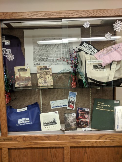 UrbanaFree's tweet image. Stopping by the Library today? Stop by the display case to see some Library swag! Pick out a gift for the Library fan in your life! #libraryswag #urbanafree
