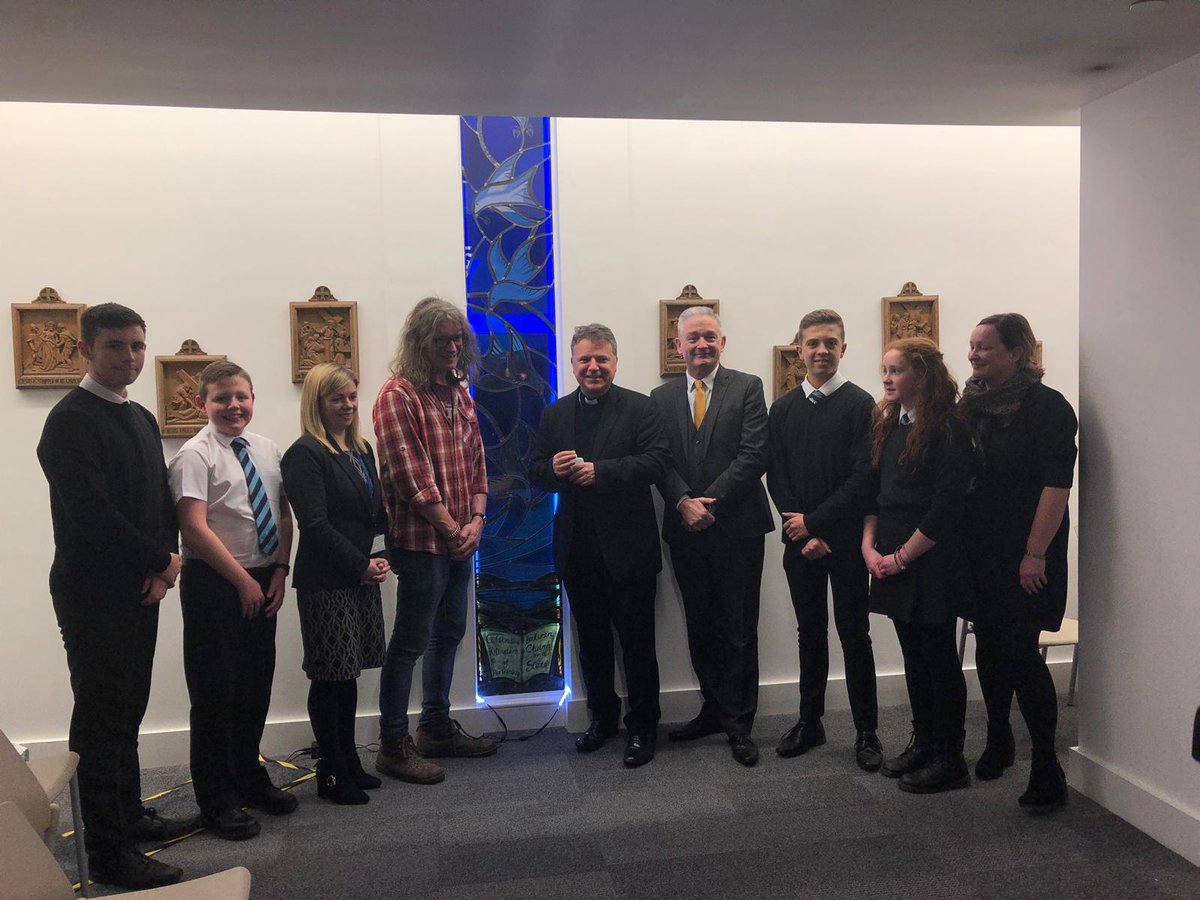 Description: 5 doves - diocese and 4 local parishes. Each dove with olive branch with Bishops staff - Faith, heart with hand in the centre - charity, heart - love, acorn - hope. Iona bay where St. Columba landed in Scotland. The blue glass - Irish Sea and Clyde and school colours