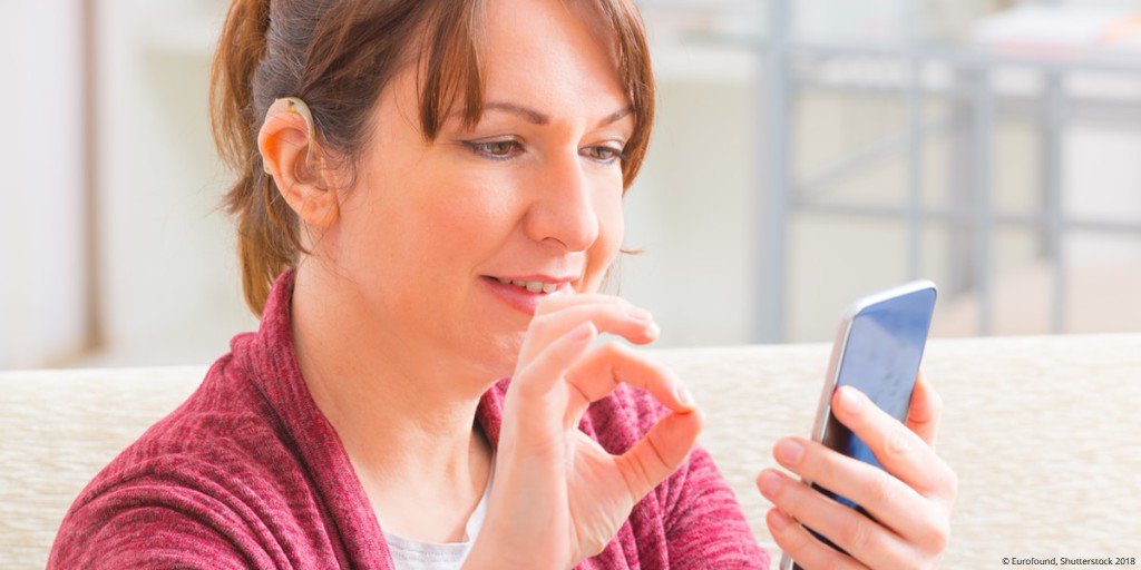 A woman looks at the screen of her smartphone.