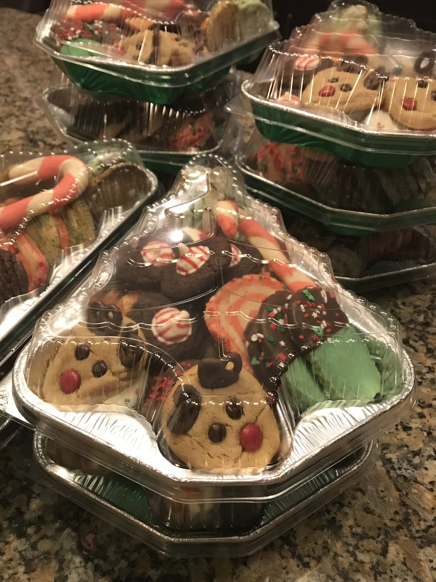 Multiple containers shaped like trees filled with various Christmas cookies