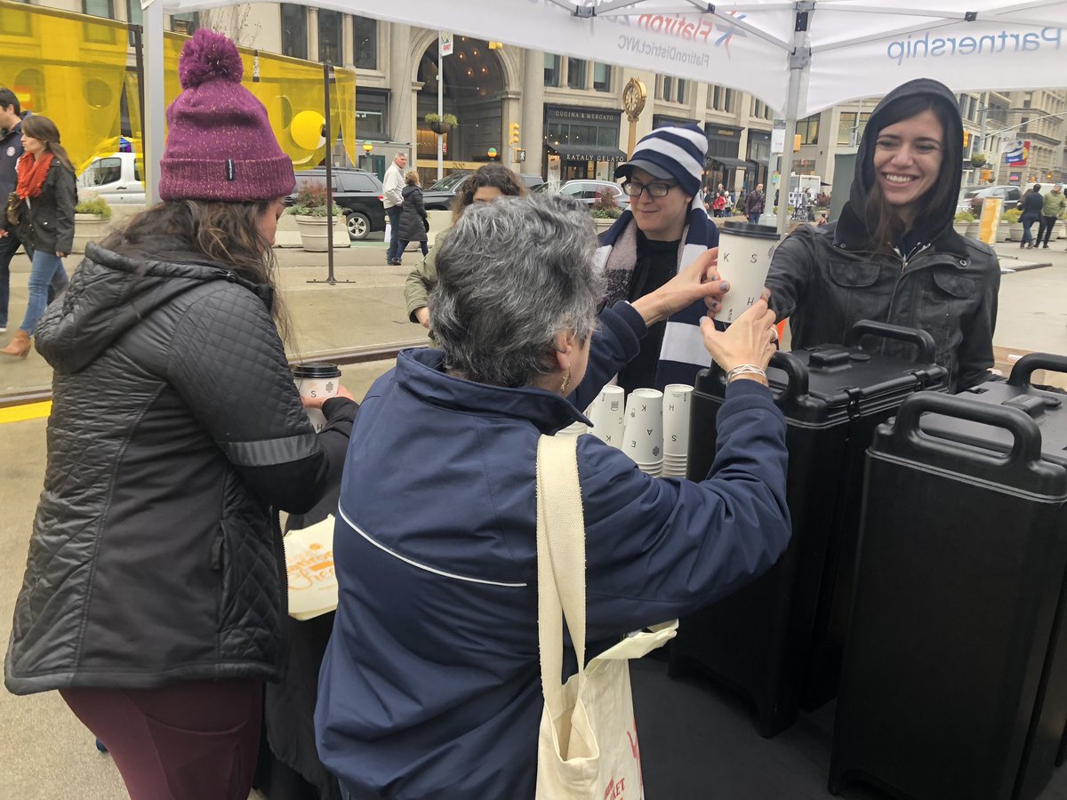 FlatironNY's tweet photo. Wet weather doesn't stop the #23DaysofFlatironCheer! Stop by 'til 4pm:

✔️ Free @shakeshack hot chocolate🍫 
✔️ Food Drive for @FoodBank4NYC🥪
✔️ @SonySquareNYC gift 🎞
✔️ Tote Bag w/discounts 🛍
✔️ Prize Wheel! 🎁

Share pics with #HappyinFlatiron for a chance to win a prize! https://t.co/wqE0cihZM7