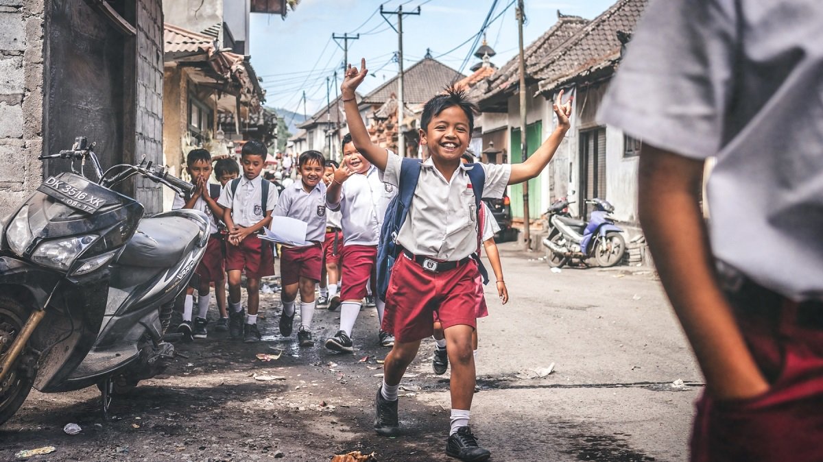 Happy school boys run through the street laughing for the camera