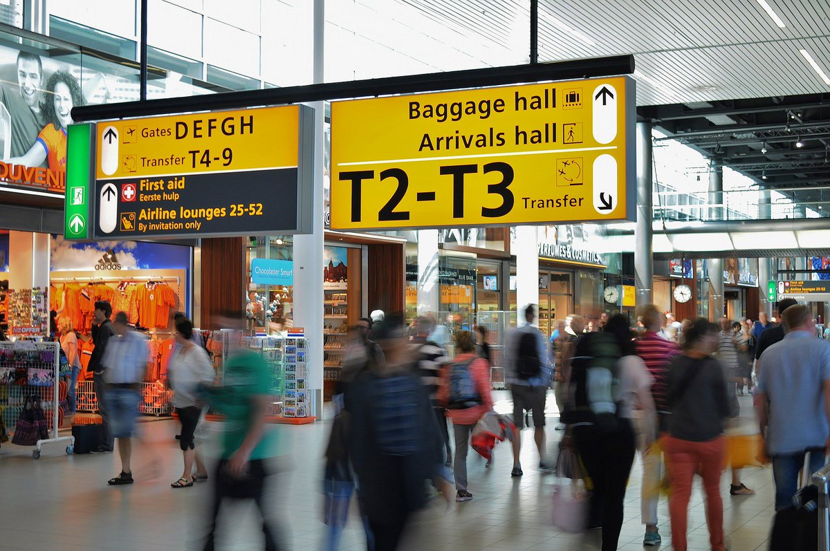 airport terminal with overhead signs, people pass by in a blur