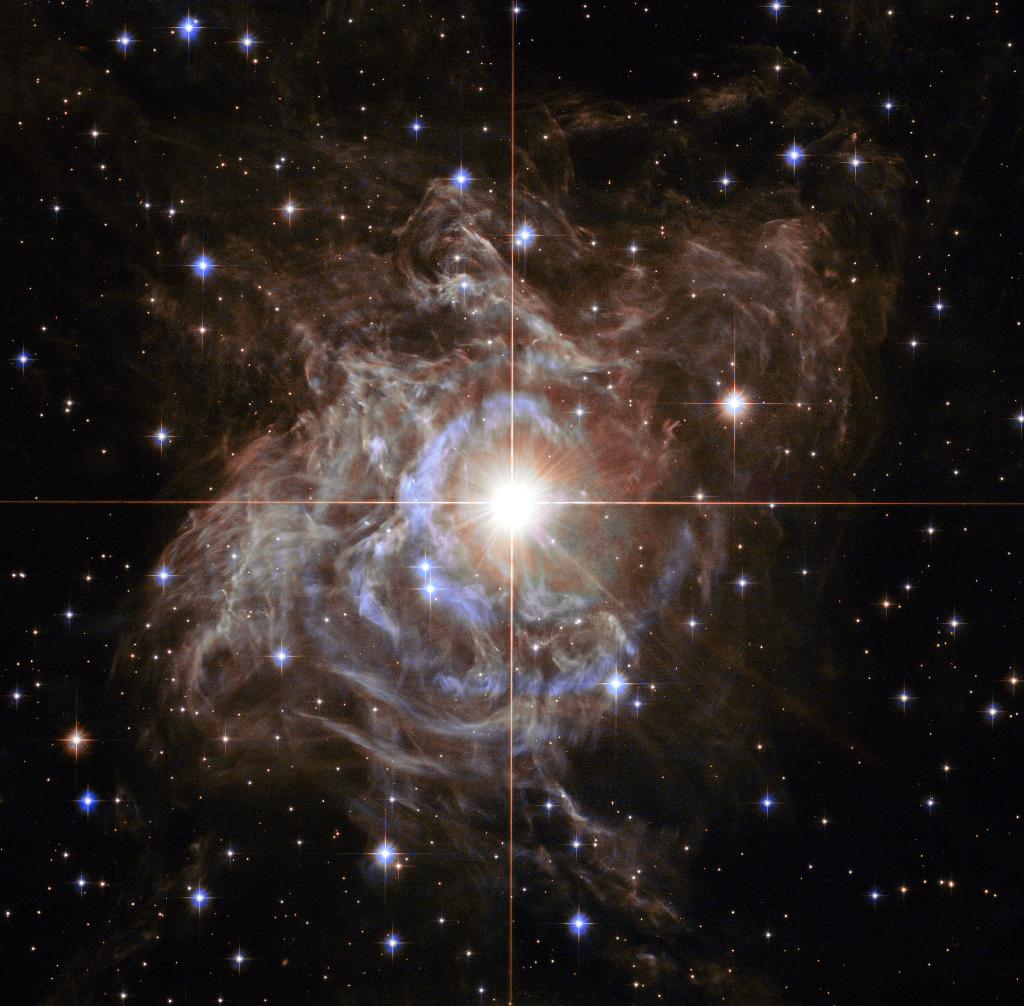 NASA's tweet photo. A celestial holiday wreath made of sparkling lights! Swaddled in a gossamer cocoon of reflective dust and illuminated, the super star in the center of this @NASAHubble image is ten times more massive than the Sun &amp; 200 times larger. Info: https://t.co/dKWJAuoS9z https://t.co/I2SitYqw9t