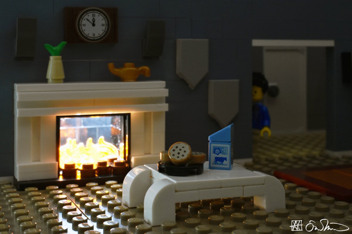 LGS stands behind a doorway and looks at a table with cookies and milk in front of the fireplace.