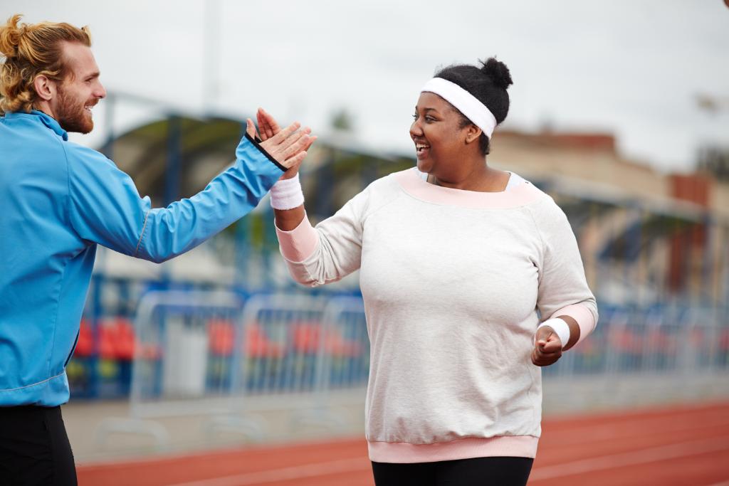 Woman exercising and high fiving friend. 