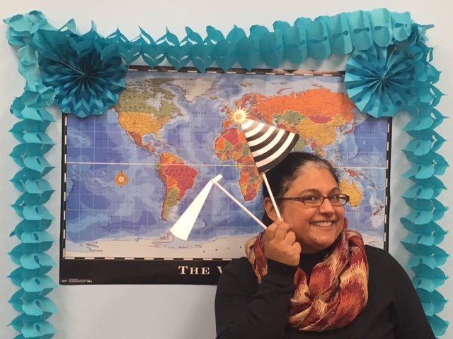 Priti posing in front of a world map background framed with blue crepe paper.