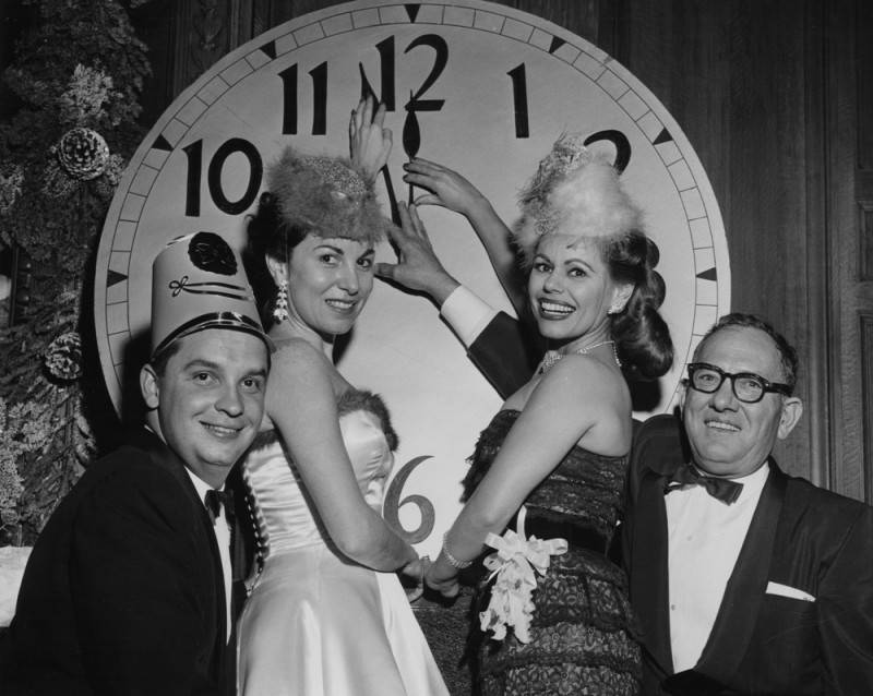 four people pointing at giant clock