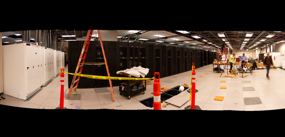 TACC's tweet photo. Busy morning in the machine room as we prepare for the Frontera supercomputer. Crews placed the transformers (white) and are building the power bus (above). https://t.co/wGKQVhodT7