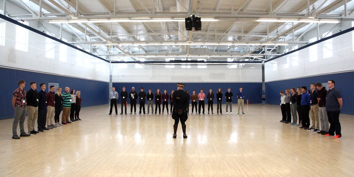 Students form a U around a police officer in centre of gym.