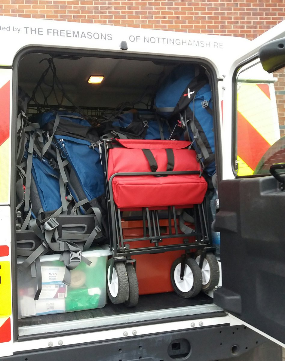 back of a Landrover, filled with boxes , rucksacks, sleeping bags and a foldaway trolley