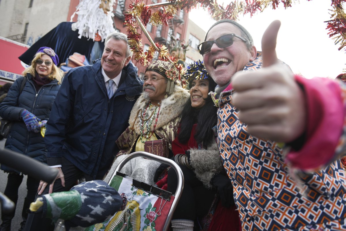 Someone gives a thumbs up to the camera while parade-goers stand with mayor