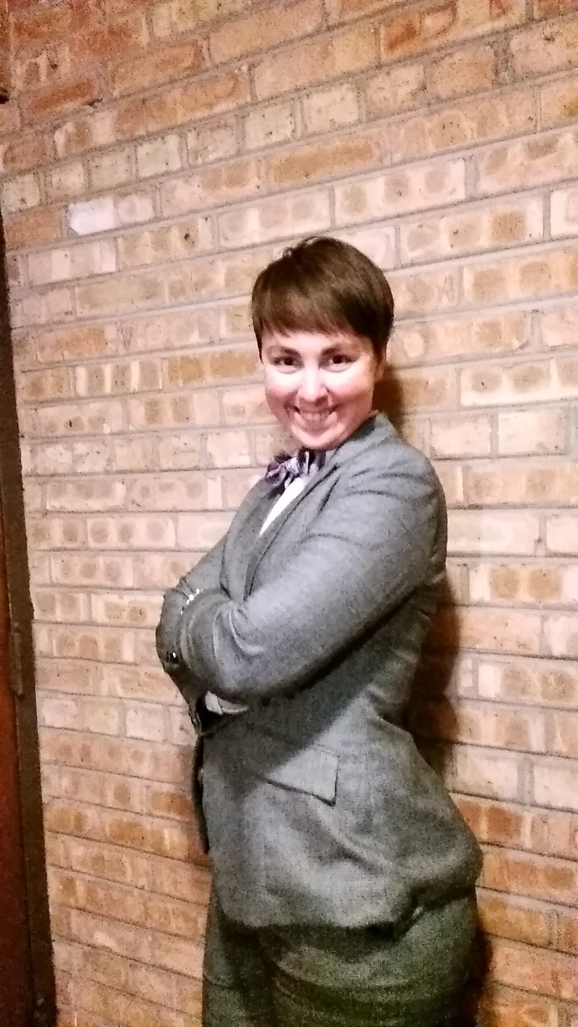 picture of me in a gray suit and purple bowtie, arms crossed, grinning at the comera