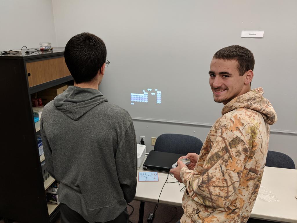 Matt and Ryan in the PHS Makerspace using a projected video game that Matt designed using C++ and a microcontroller.