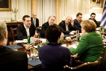 Griechenlands Ministerpräsident Tsipras unterhält sich über einen Tisch hinweg mit Kanzlerin Merkel.