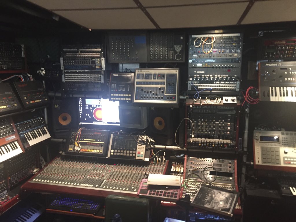 photograph of someone's studio, with a Roland TR-808, Akai MPC
	3000, Prophet V0, a mixer board, and lots of rack-mount synthesizers