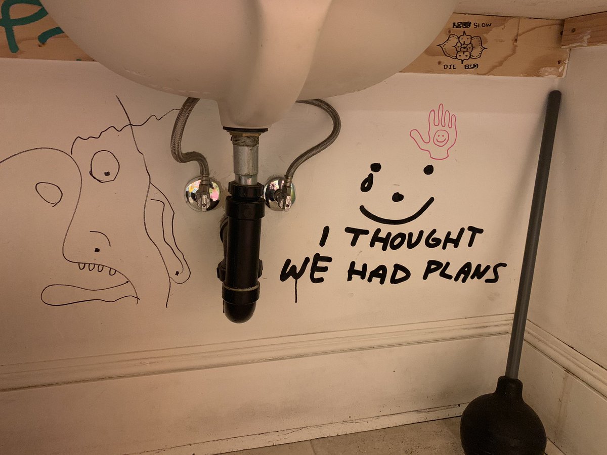 Photo of plumbing under sink with a graffito of a crying smiley and “I THOUGHT WE HAD PLANS” captioned beneath.