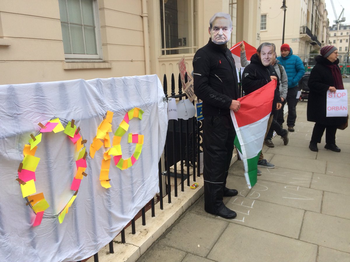 O1Gintl's tweet photo. Oooohh rare moment when George #Soros and Viktor #Orban are holding the Hungarian flag together at the Hungarian Embassy. #O1G #London protest #Hungary https://t.co/bbo3G7w5TY