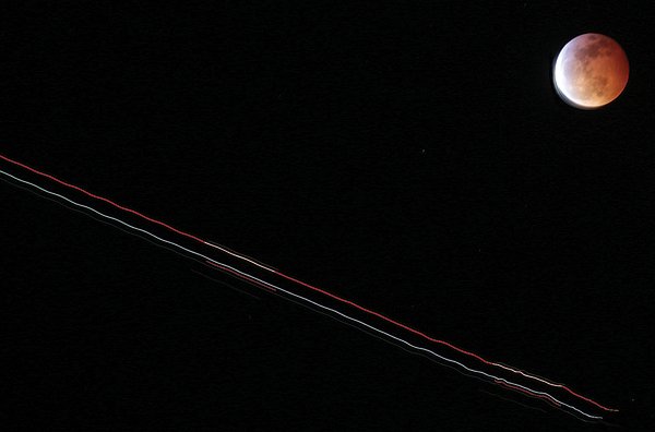 The trail of a jetliner is shown crossing the sky as the eclipse of the moon happened Sunday. #RNews@@RegPaj