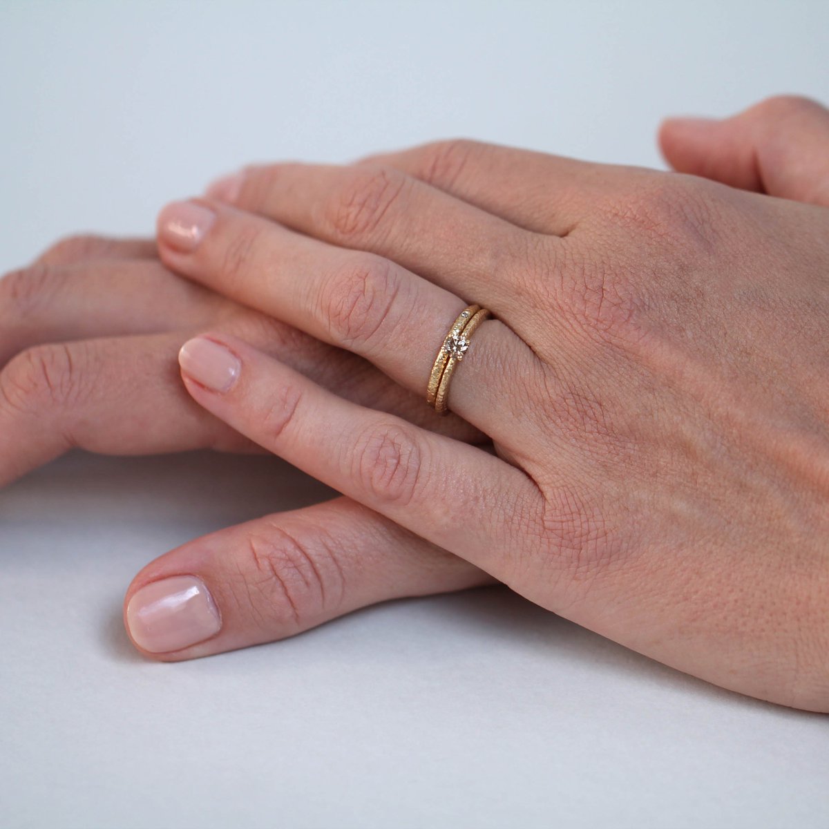 Traditionally in the UK you remove your engagement ring on the day of marriage and wear it on the right hand, it is then replaced on top of your wedding band once you’re married. 

However, there are lots of alternative ways to wear your rings as seen here.
