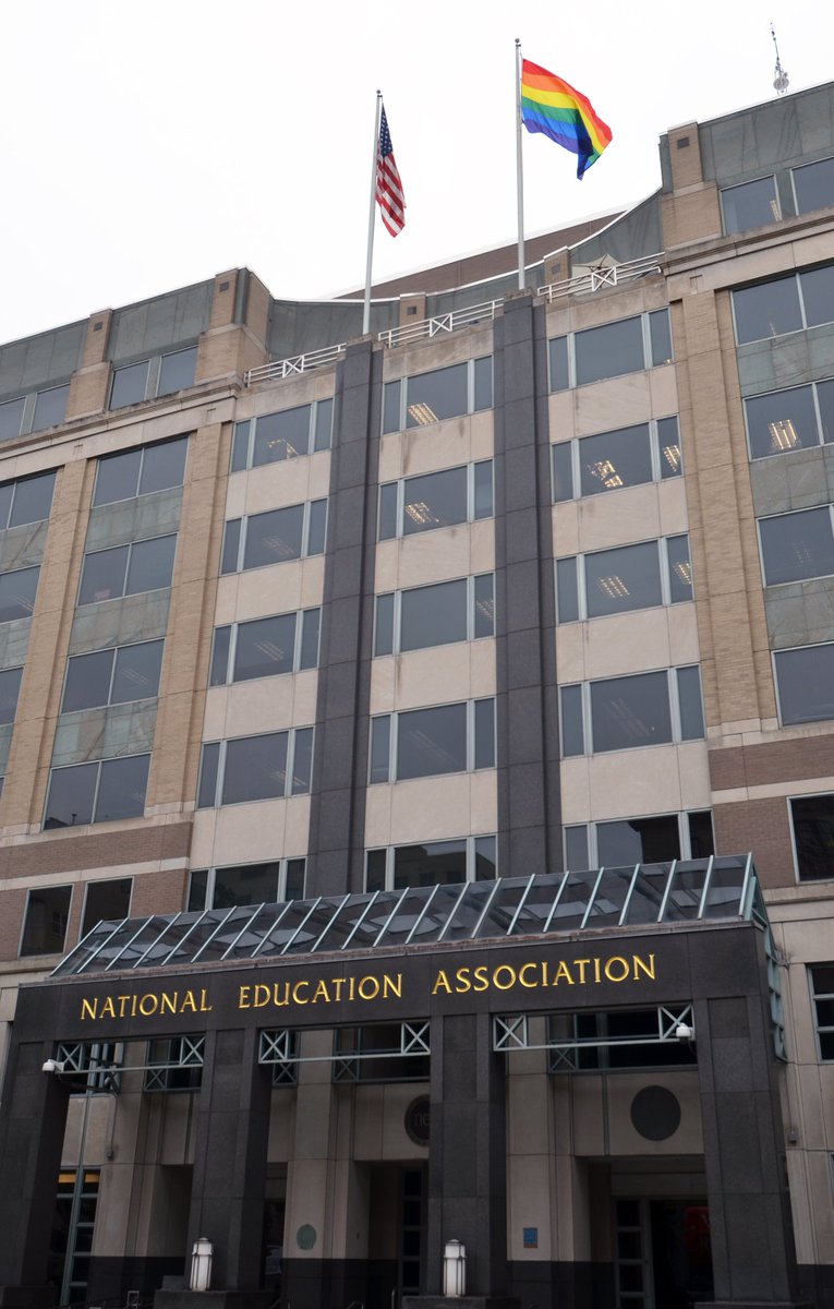 The NEA building in DC with two flags on top. The US flag is on the left and the rainbow flag is on the right.