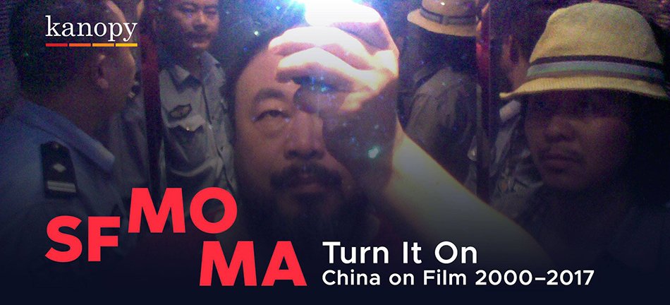 a man looking up above his head, holding a light, in a dark room