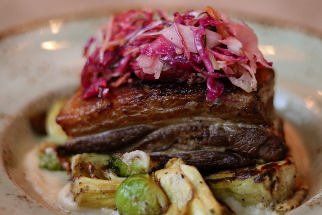 Our creative chefs are back at it again! Tonight's feature is a 7 oz braised pork belly on apple mashed potatoes with roasted lemon artichoke and brussel sprouts topped with cabbage salad!