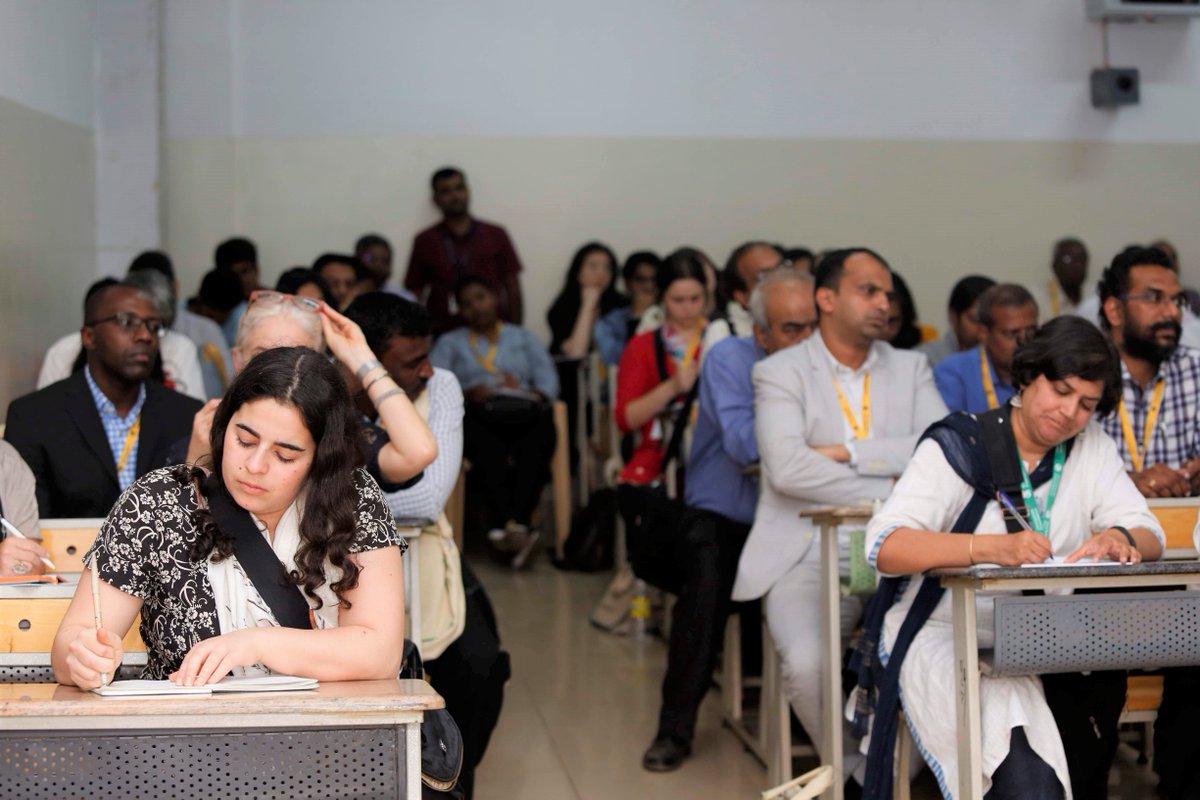 People sitting at desks and standing in a room.