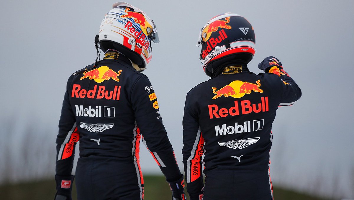 Max and Pierre in their race suits and helmet taken from behind.