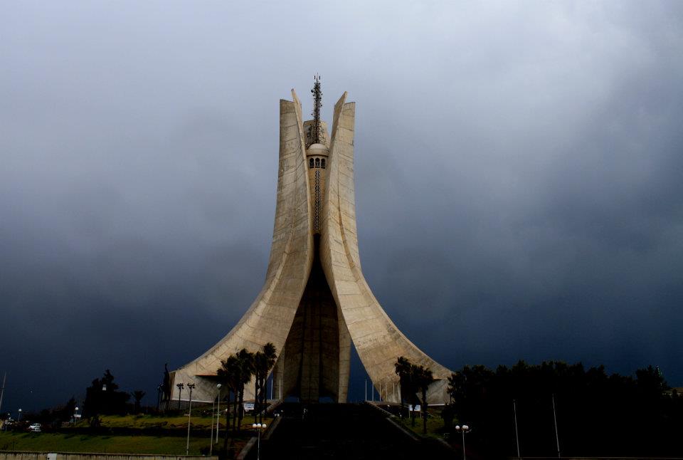 Algiers, Algeria - the Martyrs' Memorial. You're looking at a photo I took head-on, then the cityscape - as well as two images of me basically doing yoga on top of the IMAX theater podium with geolocation data of the memorial for reference, before we zoomed in...WAY WAY WAY IN.