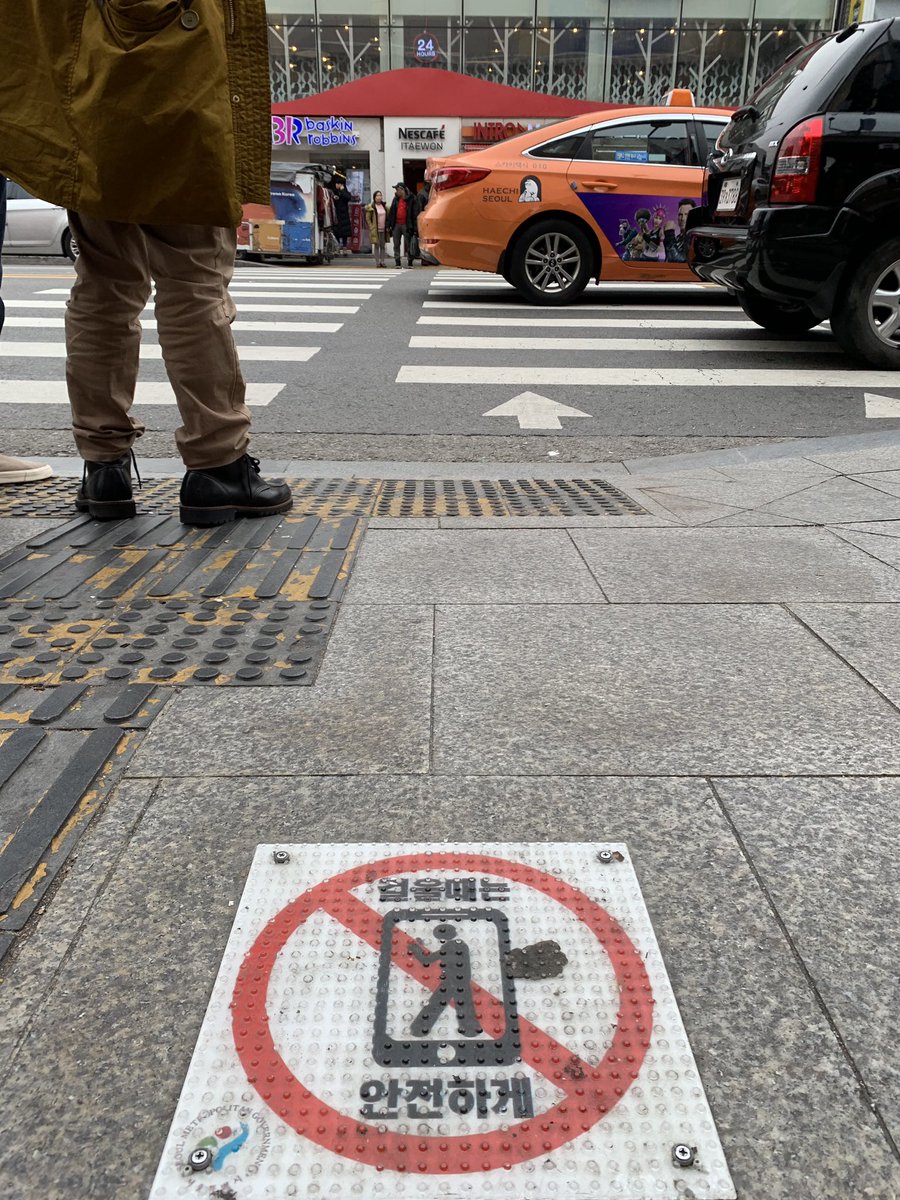 ltcooper's tweet image. There are now signs on the sidewalk near some crosswalks in Seoul reminding you to get off your phone while you're crossing the street for safety.