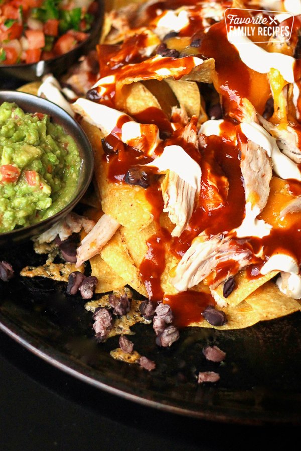 These BBQ Pulled Pork Nachos will rival anything that you can order at a restaurant. Pulled pork, BBQ sauce, black beans, melted cheddar, and sour cream. #bbq #pulledpork #nachos #bbqpulledpork #bbqpork #bbqnachos #bbqpulledporknachos #restaurantnachos favfamilyrecipes.com/restaurant-sty…