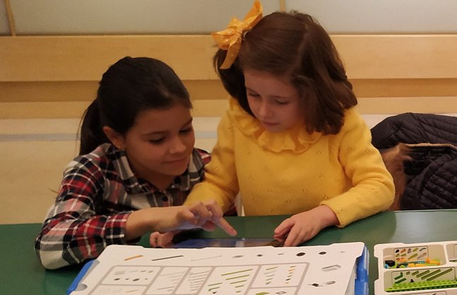 Dos niÃ±as montando un vehÃ­culo espacial robotizado con piezas lego.