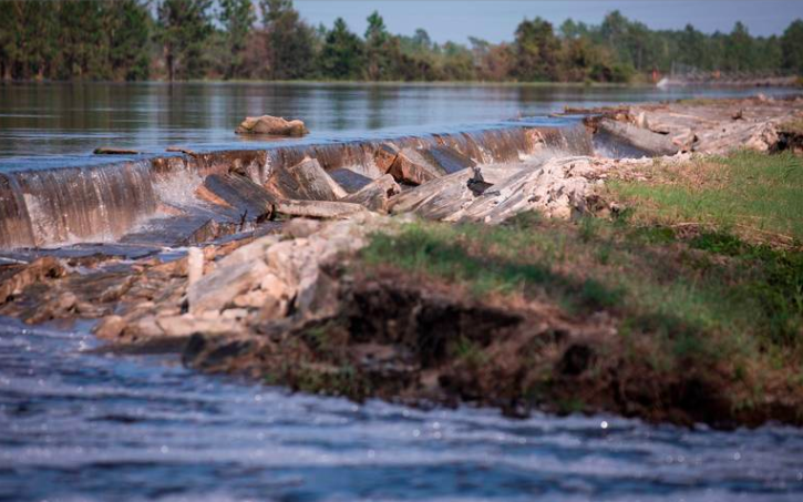MooreCharitable's tweet photo. The earthen berm around #SuttonLake, which contained #coalash from a nearby pond, collapsed in many places due to the aftermath of Hurricane #Florence. Shouldn't NC move the cleanup forward? https://t.co/mD46jdqYsC https://t.co/PgQ07rUQwA