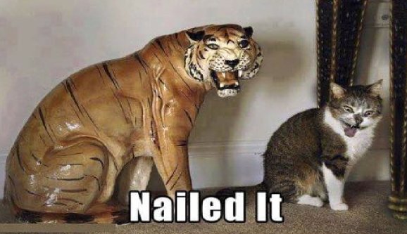 Picture of a statue of a tiger with its mouth open and fangs bared beside a kitten or young cat whose eyes are almost crossed while it has its tongue out. Text overlay is "Nailed It."