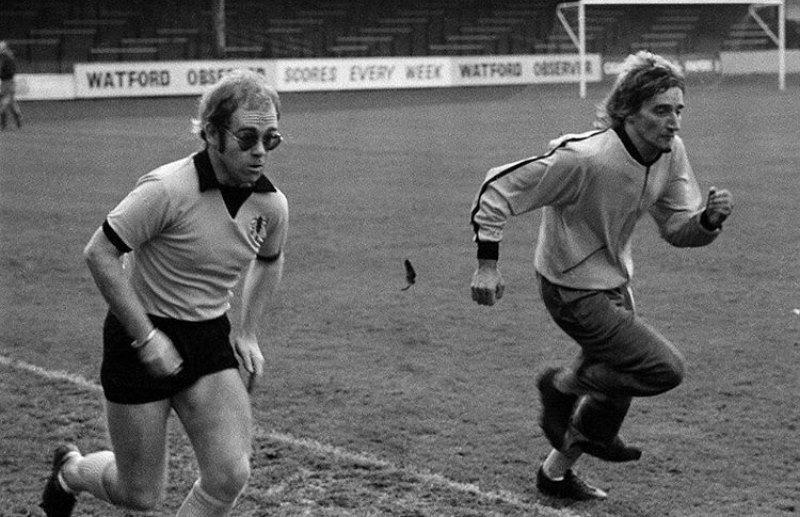 Elton John and Rod Stewart 'training' at Watford F.C.'s Vicarage Road stadium. 1973 or 1974