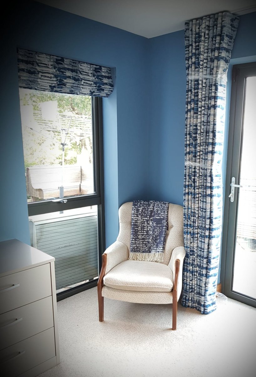 Wave headed curtains hung on a ceiling track paired with a Roman blind