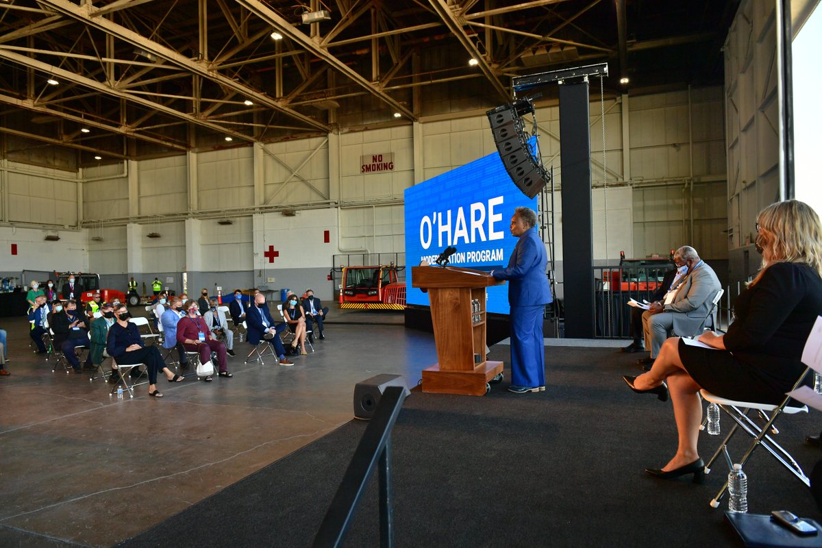 Mayor Lori E. Lightfoot is standing in front of a group in an airport hanger.