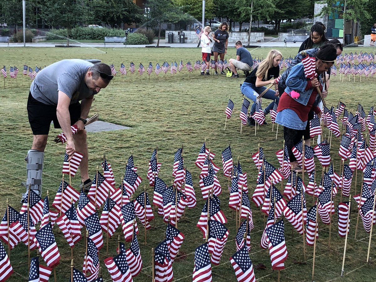 WCCBCharlotte's tweet photo. Volunteers are at Romare Bearden Park putting 2,977 American flags into the ground in the shape of the twin towers. Each will have the name and picture of a person lost that day. The #flagsofremembrance will be on display till Monday. #September11 https://t.co/KMomW1eDlU