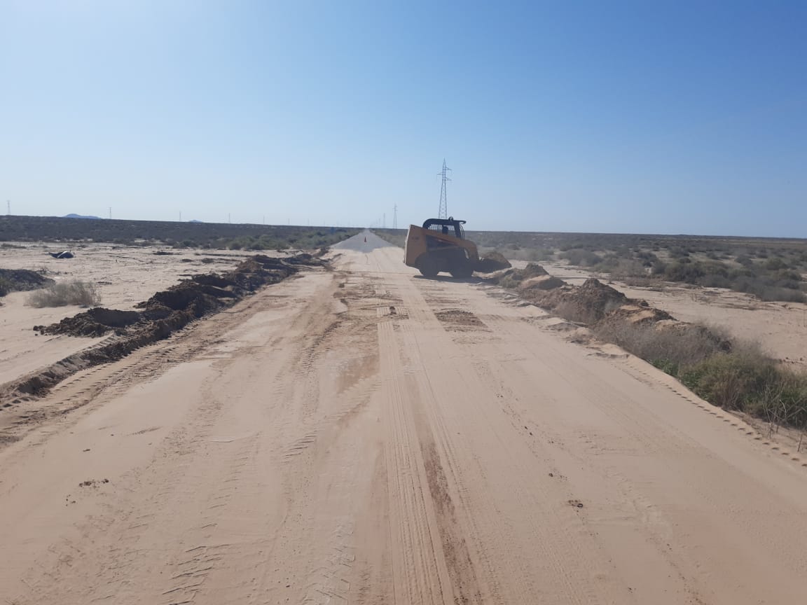 La Residencia de Caborca realiza labores en la carretera de Puerto Peñasco Est. Sahuaro con personal de campo y maquinaria, retirando el material producto del arrastre por cruce de la marea alta sobre la superficie de rodamiento, por seguridad de los usuarios.